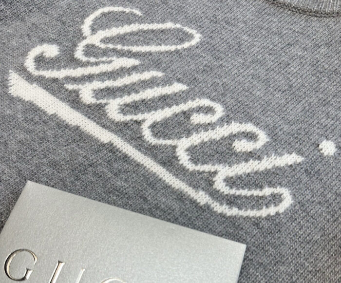 Maglione Gucci grigio con logo elegante, dettagli di lusso e tessuto morbido di alta qualità.