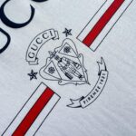 Maglietta Gucci con logo, emblema storico e strisce rosse, stile moderno e lusso Italiano.