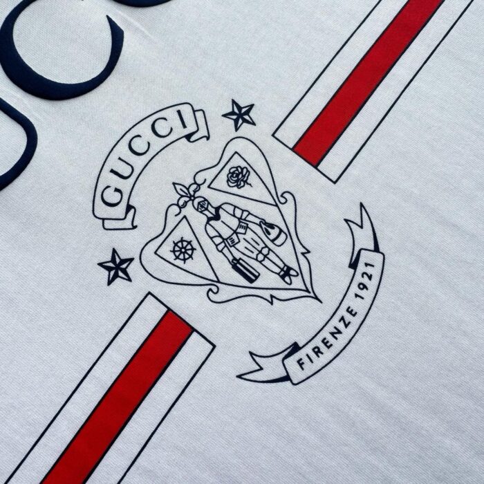Maglietta Gucci con logo, emblema storico e strisce rosse, stile moderno e lusso Italiano.