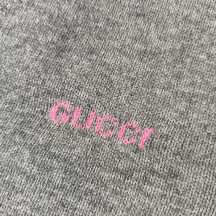 Logo Gucci rosa su tessuto grigio di alta qualità, stile elegante e moderno.
