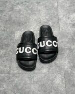 Sandali Gucci slide neri con logo bianco, stile casual e di lusso, massima comodità.
