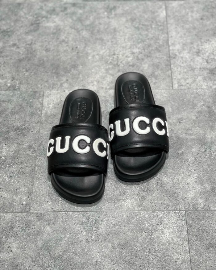 Sandali Gucci slide neri con logo bianco, stile casual e di lusso, massima comodità.