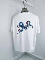 T-Shirt Gucci bianco con grafica artistica, serpenti colorati e logo stilizzato.