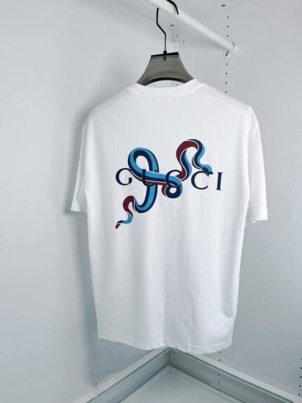 T-Shirt Gucci bianco con grafica artistica, serpenti colorati e logo stilizzato.