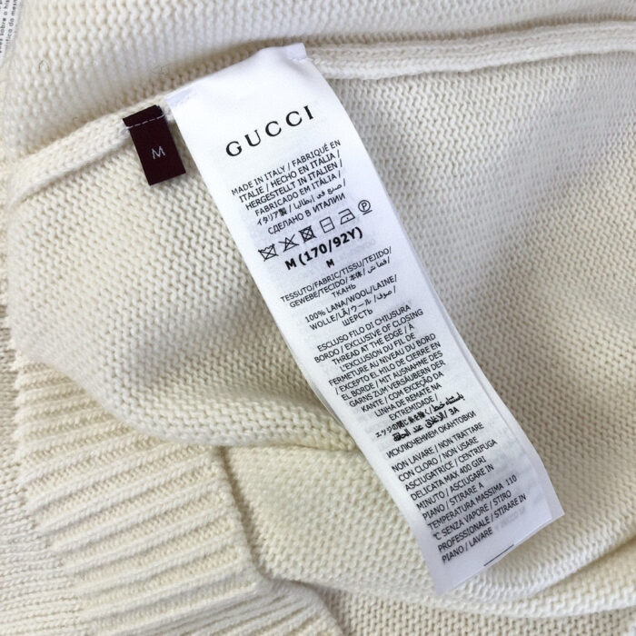 Etichetta interna Gucci su maglione in cashmere, con istruzioni di cura multilingua e tag M.