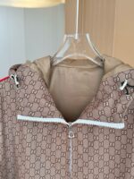 Giaccone Gucci marrone con logo doppio G, cappuccio e dettagli rossi, stile elegante e pratico.