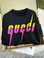Maglietta Gucci nera con design colorato, scoperta in scatola, stile streetwear trendy.