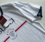 T-shirt Gucci bianco con logo, dettaglio scudo e finiture navy elegante e casual.