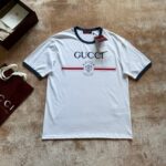 Maglietta Gucci bianca con logo, dettagli sportivi e borsa di lusso elegante.