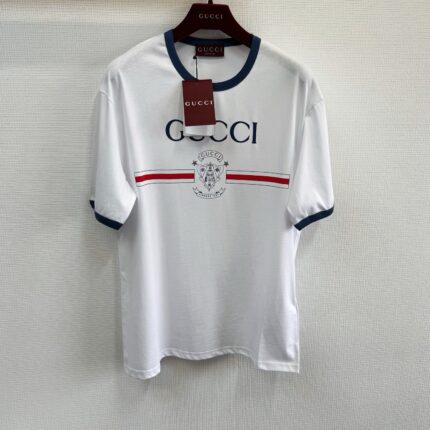 Maglietta Gucci bianca con logo, strisce rosse e navy, stile casual e di lusso.