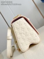Borsa di lusso crema con motivo embossato, chiusura oro, interno rosa e tracolla regolabile.
