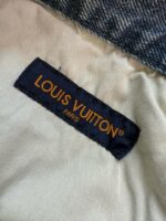Etichetta Louis Vuitton su denim, logo in arancione su sfondo blu, simbolo di lusso e qualità.