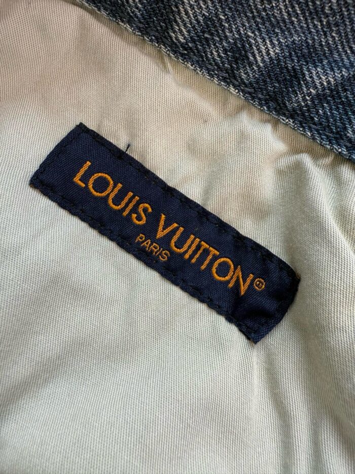 Etichetta Louis Vuitton su denim, logo in arancione su sfondo blu, simbolo di lusso e qualità.