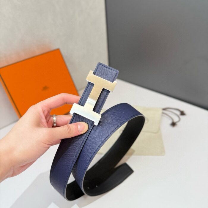 Cintura in pelle navy con fibbia dorata geometrica, accessorio di moda elegante e versatile.