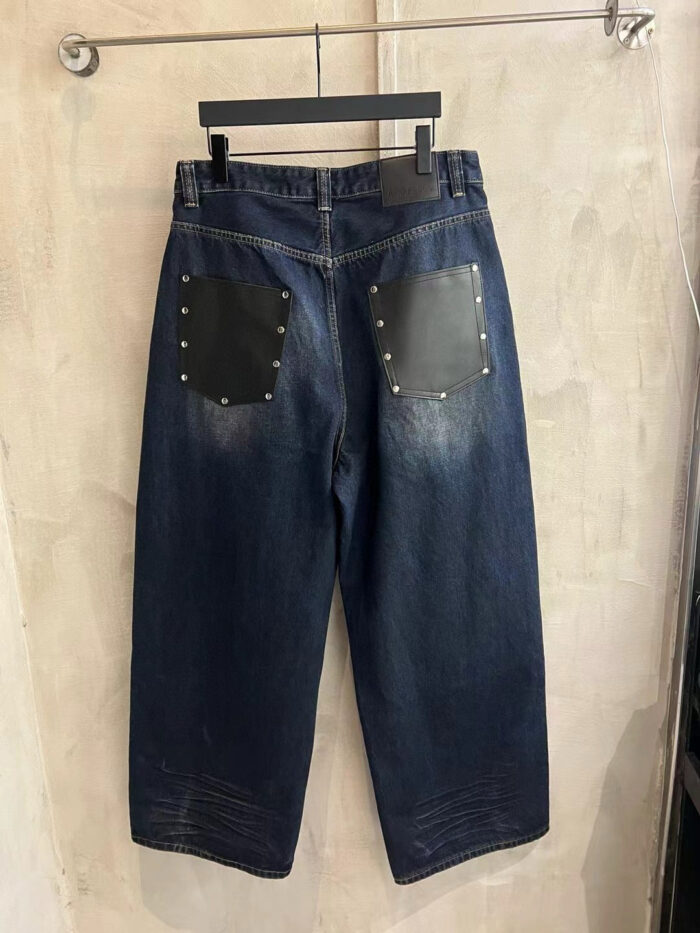 Jeans denim nero con tasche in pelle, borchie e dettagli vintage, stile streetwear moderno.