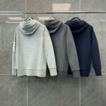 Felpe con cappuccio grigie, navy e charcoal in esposizione moderna su parete di piastrelle.
