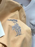 Felpe beige e bianca con grafica di cavaliere medievale, stile casual e artistico, perfette per appassionati.