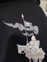Cavaliere medievale con bandiera e armatura in argento e oro su sfondo nero.
