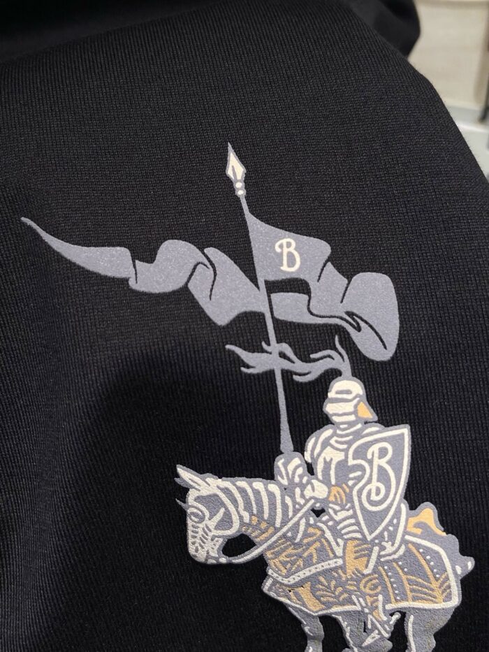 Cavaliere medievale con bandiera e armatura in argento e oro su sfondo nero.