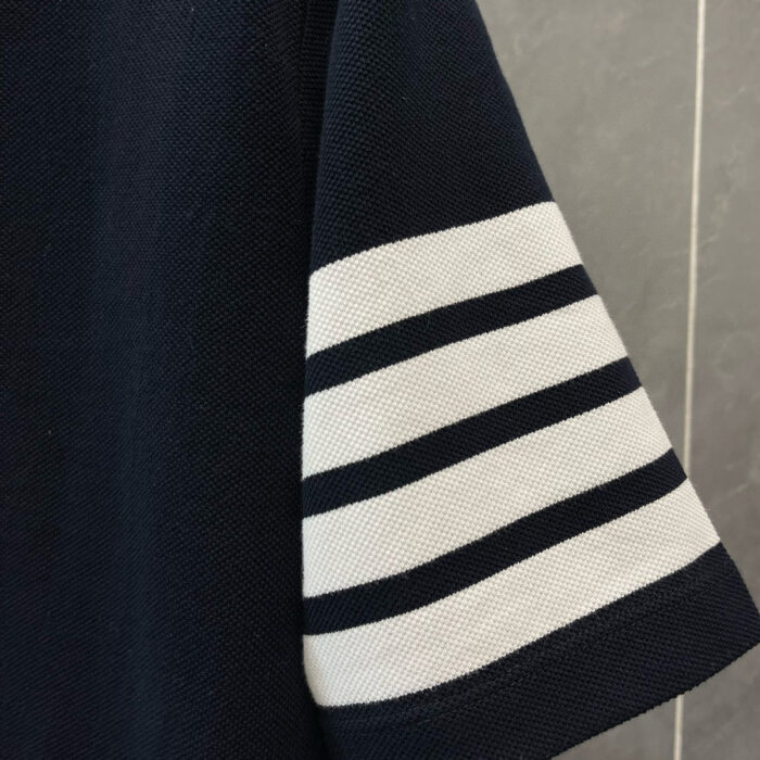 Manica di camicia navy con strisce bianche orizzontali, stile nautico e dettagli curati.
