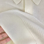 Maglietta polo in maglia color crema, dettaglio tessuto e collo elegante, ideale per look casual e raffinati.