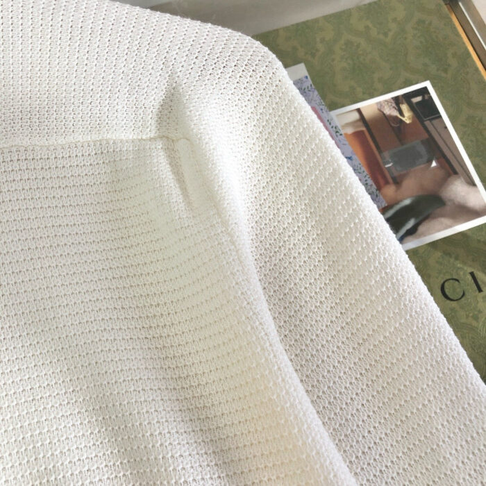 Look casuale con maglia bianca e libri eleganti in un ambiente rilassante e raffinato.