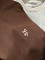 Magliette casual a strati bianco e marrone con logo ricamato, stile trendy e versatile.