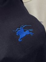 Polo con logo ricamato di cavallo blu, stile elegante e comfort quotidiano.