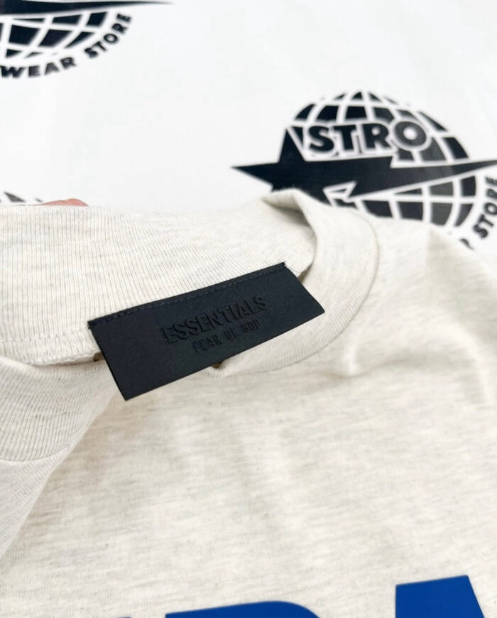 Maglietta beige con etichetta minimalista e logo globale sullo sfondo, stile casual e moderno.