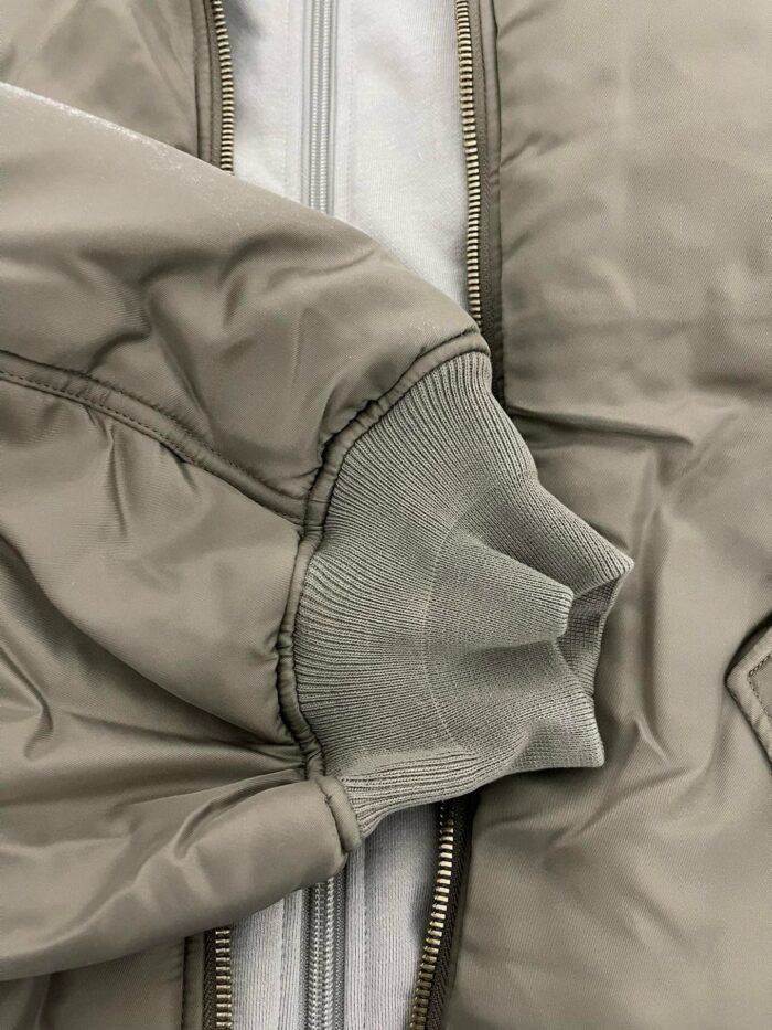 Giacca beige leggera con polsino grigio in tessuto rifinito e chiusura a zip.
