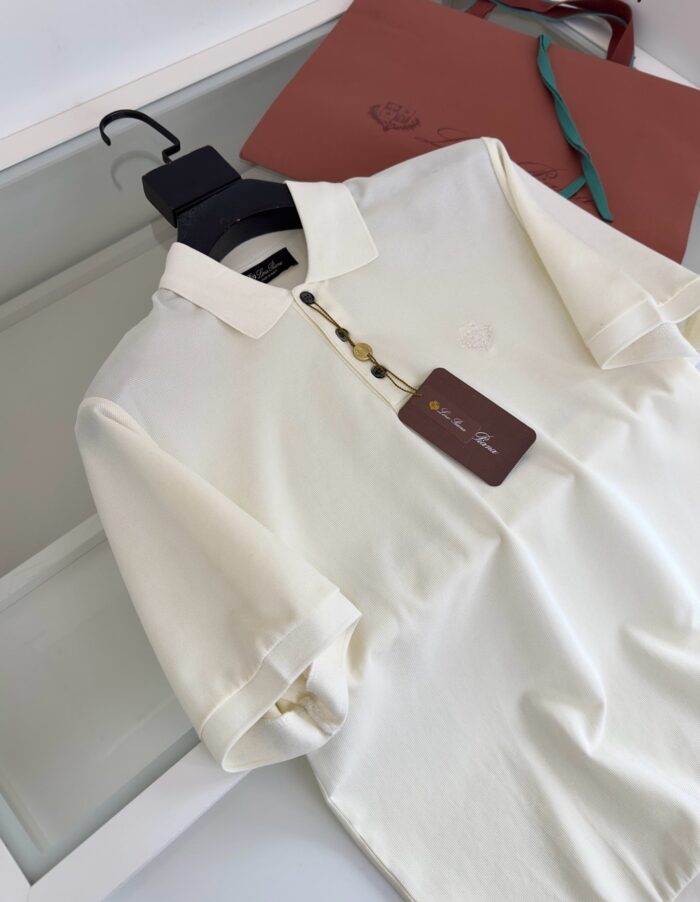 Maglietta polo beige con dettaglio elegante e tracolla in pelle marrone.