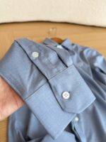 Polsino di camicia blu chiaro con doppio bottone e cuciture dettagliate.