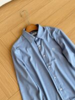 Camicia uomo blu chiaro elegante su appendiabiti in legno, stile formale e raffinato