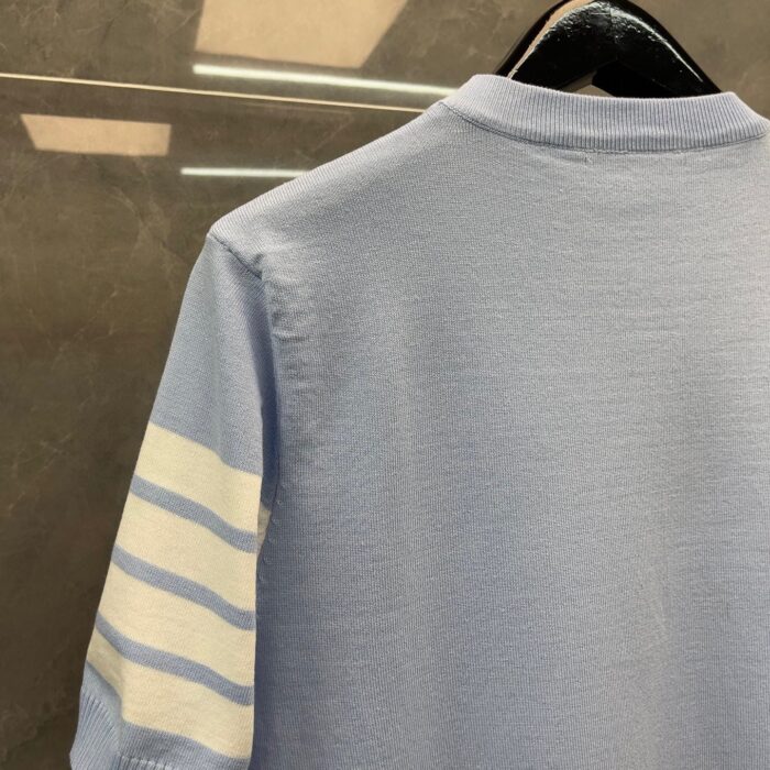 Maglietta polo azzurra con strisce sportive bianche, stile casual e moderno.