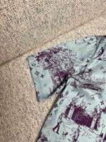 Camicia verde con stampe artistiche di natura e dettagli eleganti in contrasto.