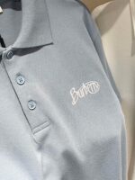 Maglietta polo blu chiaro con logo ricamato bianco, stile elegante e casual in cotone leggero.