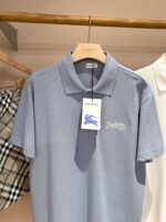 Maglietta polo grigia su appendino con etichetta blu in negozio, stile casual e elegante.