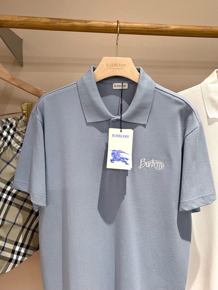 Maglietta polo grigia su appendino con etichetta blu in negozio, stile casual e elegante.