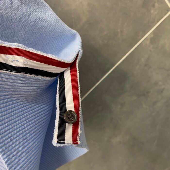 Camicia polo blu chiaro con dettagli a righe, bottoni e stile sportivo elegante.