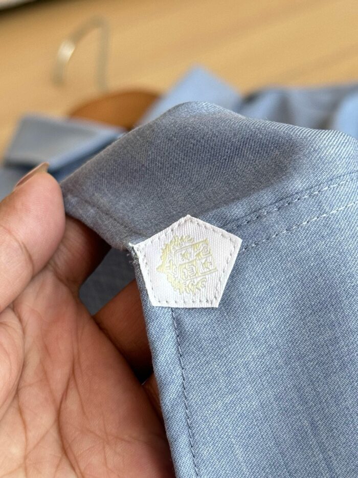 Camicia blu chiara con etichetta pentagonale elegante e dettagli di alta qualità.