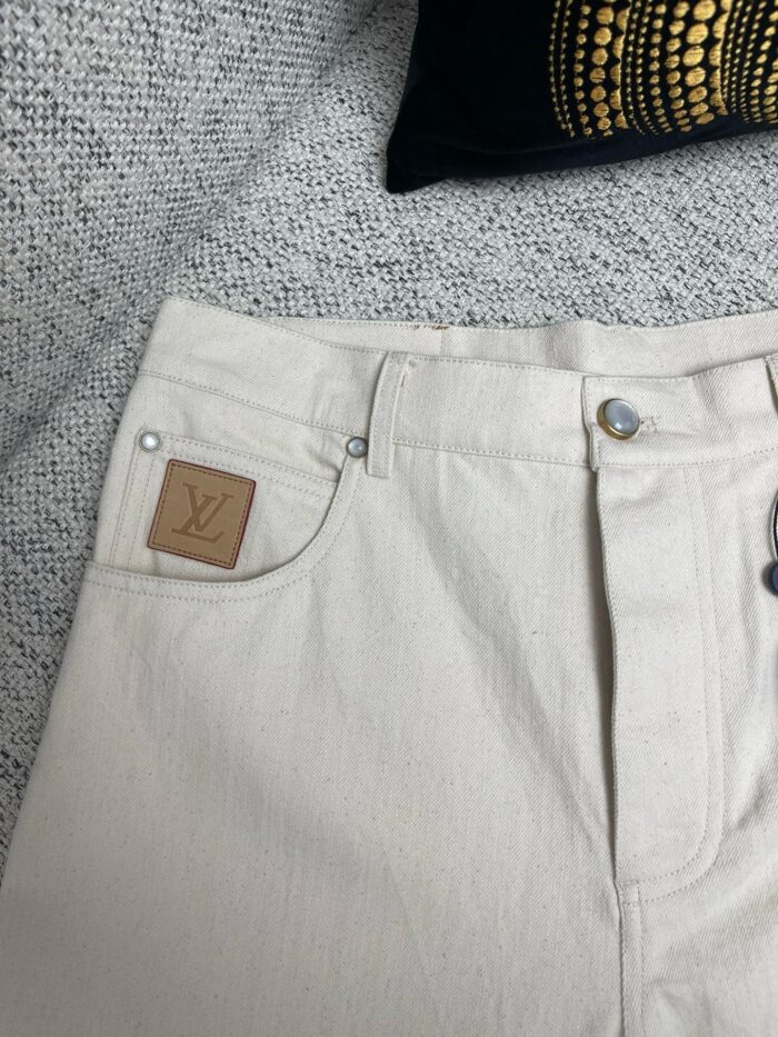 Pantaloni chiari in denim con logo in pelle, stile chic e versatile per ogni look.