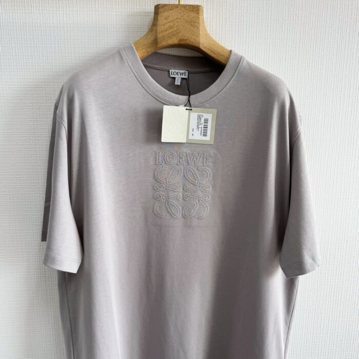 T-shirt grigia chiara minimalista con logo embossato, in cotone morbido, eleganza discreta.
