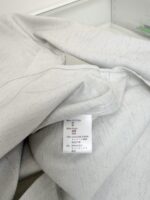 Tessuto grigio chiaro con etichetta di cura, perfetto per abbigliamento casual e confortevole.