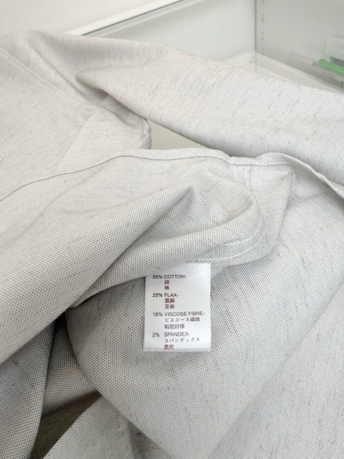 Tessuto grigio chiaro con etichetta di cura, perfetto per abbigliamento casual e confortevole.