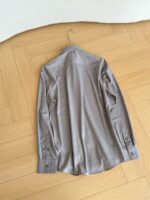 Camicia grigia a maniche lunghe su pavimento in legno naturale, stile casual ed elegante.