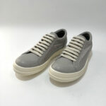 Sneakers moderne in pelle grigia chiara, comode, con suola spessa e dettagli eleganti.