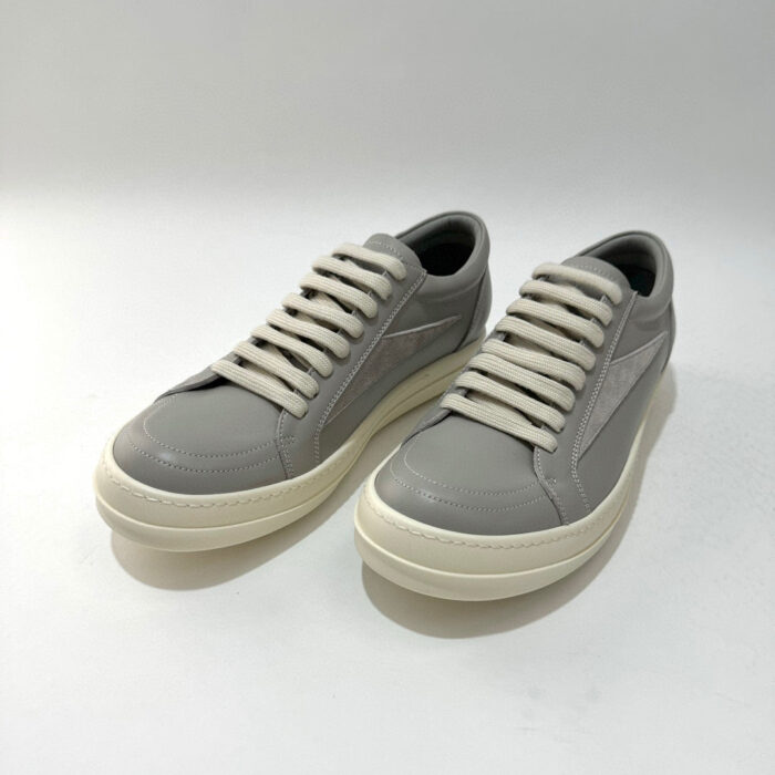Sneakers moderne in pelle grigia chiara, comode, con suola spessa e dettagli eleganti.