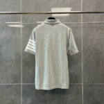 Maglietta polo grigia con strisce sportive bianche, stile casual e moderno, sfondo elegante.