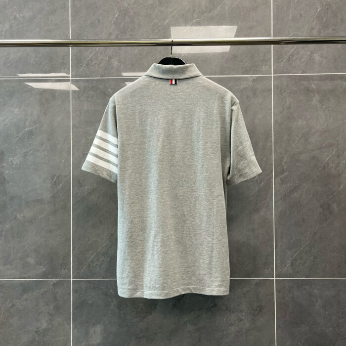 Maglietta polo grigia con strisce sportive bianche, stile casual e moderno, sfondo elegante.