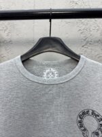 T-shirt grigia a costine con design grafico circolare, stile casual e moderno.